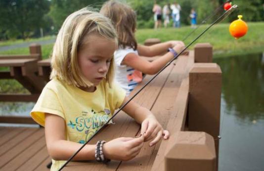 A young girl baits a hook at a fishing dock 