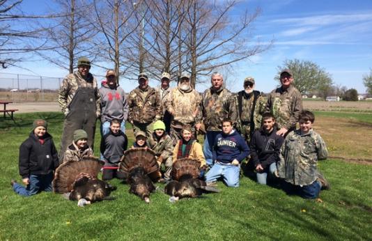 A group of youth turkey hunters and their mentors show off their harvest.