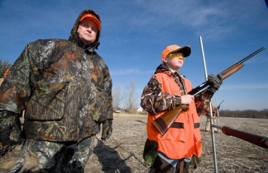 An adult man and young boy learning gun and hunter safety.