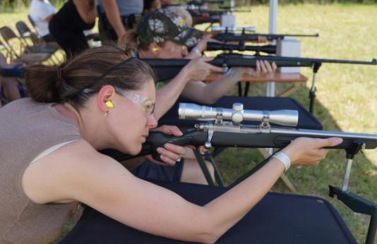 A woman shooting a rifle at a shooing range.