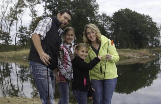 A family poses with a fish they caught on a fishing trip.