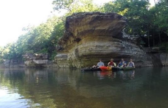 four canoeists and kayakers pose in their watercrafts on the Big Piney River