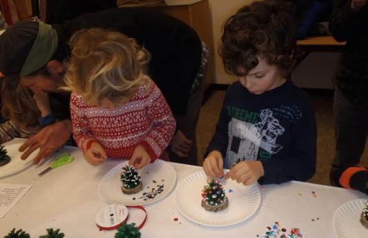 two kids make nature-themed crafts at a table