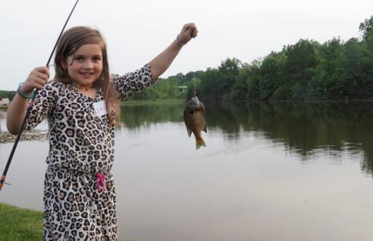 A little girl poses with a fish she caught at a Columbia pond.