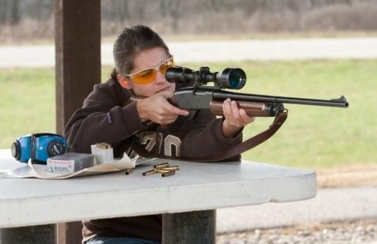 woman shoots rifle at shooting range