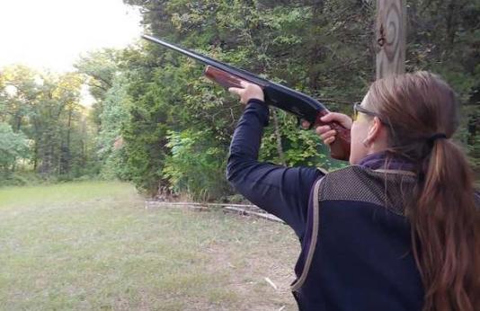 woman shooting shotgun in field
